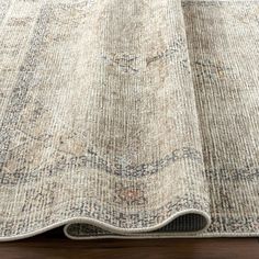 a large rug with an intricate design on the bottom, and a wooden floor below it