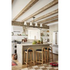 a kitchen with two stools and an island in the middle of it, surrounded by wood beams