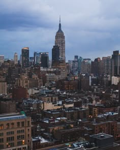 the city skyline is lit up at night, with tall buildings in the background and dark clouds overhead