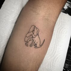 a small black and white dog tattoo on the left arm with a person hugging it's head