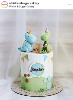 a birthday cake for a baby boy with two dinosaurs on top and one dinosaur in the middle