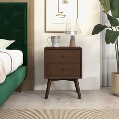 a bed with a green headboard and nightstand next to a plant in a bedroom