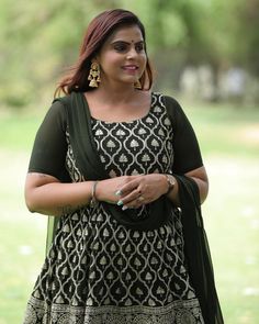 a woman in a black and white dress standing on grass with her hands clasped to her chest