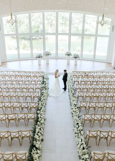 a bride and groom standing at the end of an aisle in front of rows of chairs