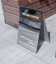 a sign that is on the side of a building next to a bench with a coffee bag in it