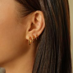 a close up of a person wearing gold earring with two rings on their ears