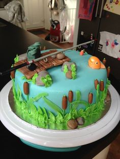 a blue cake with green frosting and an orange fish on top