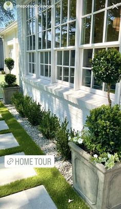 a white house with some plants in front of it and the words home tour written below