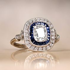 a fancy ring with an oval cut diamond surrounded by blue and white diamonds