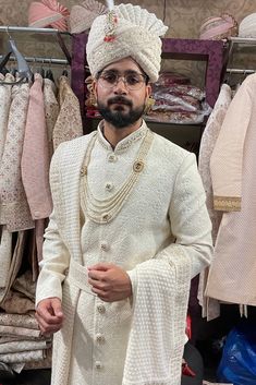 a man standing in front of a rack of clothes wearing a white sherve