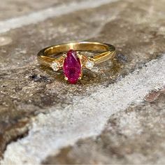 a gold ring with an oval shaped ruby stone and two small white diamonds on it