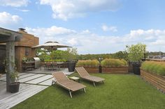 two lawn chairs sitting on top of a lush green field next to a wooden deck