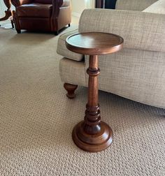 a wooden table sitting in the middle of a living room next to a couch and chair