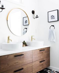 a bathroom with two sinks and a large round mirror above the sink, along with black and white checkered flooring