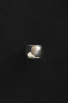 a silver ring on a black surface with the light reflecting off it's side