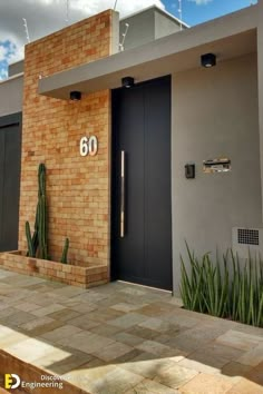 a brick building with two black doors and a cactus