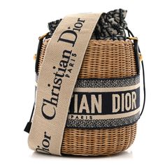 This is an authentic CHRISTIAN DIOR Wicker Oblique Drawstring Bucket Bag in Blue. This small bucket-style bag is crafted of wicker with Dior monogram canvas and blue leather and embroidered Christian Dior logo trim. The bag features an adjustble beige and blue canvas shoulder strap and aged gold hardware. The center canvas interior opens with a cinch cord to a patch pocket. Designer Woven Leather Bucket Straw Bag, Designer Woven Leather Straw Bucket Bag, Designer Woven Leather Bucket Bag, Luxury Woven Leather Straw Bucket Bag, Luxury Straw Bucket Bag With Woven Leather, Designer Woven Bucket Shoulder Bag, Luxury Woven Bucket Shape Bag, Luxury Beige Basket Bucket Bag, Designer Woven Bucket Bag