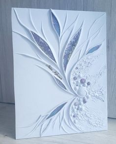 a close up of a greeting card with white paper and silver foil leaves on it