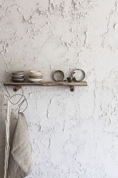 a shelf with plates and bowls on it against a white wall, next to a towel rack