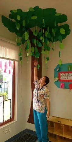 a woman standing in front of a tree made out of paper