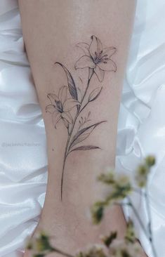 a woman's foot with a flower tattoo on her left leg and flowers in the background