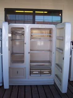 an open refrigerator sitting on top of a wooden floor