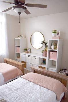 two twin beds in a bedroom with white walls and pink bed linens on them