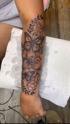 a woman's leg with a butterfly tattoo on it and flowers in the background