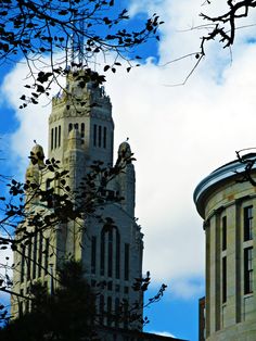 two tall buildings with clocks on them against a blue sky and white clouds in the background