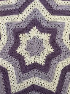 a purple and white crocheted blanket with stars on it