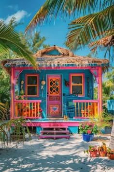 a brightly colored house on the beach with palm trees and potted plants around it