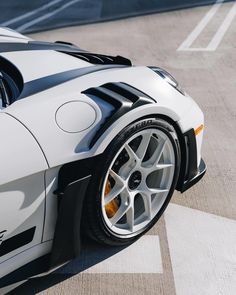 a white and black sports car parked in a parking lot with no one around it