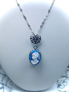 Simulated Blue & White Portrait Cameo Sterling Silver Pendant NecklaceEdward Design#P70 Introducing the Edward Design P70 Blue Cameo Portrait Pendant! This exquisite pendant is sure to make a lasting impression with its timeless, romantic design. Crafted from sterling silver and encrusted with a captivating 14mm by 10mm simulated Blue Cameo, you won't be able to resist the vintage Victorian style created by this remarkable piece of jewelry.The filigree detailing of the pendant and its bail adds Blue Cameo Jewelry For Formal Occasions, Formal Blue Cameo Jewelry, Blue Cameo Necklace For Formal Occasions, Edwardian Necklace, Filigree Necklaces, White Portrait, Romantic Design, Cameo Pendant, Sterling Silver Filigree