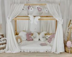 a canopy bed with pink and white pillows in a child's playroom area