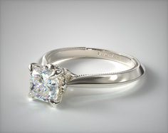 an engagement ring with a square cut diamond in the center, on a white background