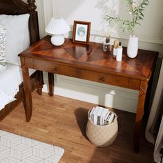 a wooden desk with two vases on top of it next to a lamp and bed