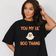 "\"Get Ready to Haunt the Laughs with Our Ghost Shirt - 'You My Lil Boo Thang'!  Looking for a hilarious twist on Halloween fashion? Look no further! Our Ghost Shirt is the perfect addition to your wardrobe for a dose of laughter and spooky charm. With the cheeky message 'You My Lil Boo Thang,' this funny Halloween shirt is sure to turn heads and spark conversations. Whether you're planning a night of Halloween fun or just want to add a touch of humor to your day, our Ghost Shirt has you covered Black Slogan T-shirt For Halloween, Halloween Novelty Tops With Funny Text, Funny Halloween Tops With Text, Funny Halloween Tops With Letter Print, Halloween Crew Neck Top With Funny Text, Funny Letter Print Tops For Halloween, Casual Halloween Tops With Funny Text, Casual Tops With Funny Text For Halloween, Funny Halloween Shirt With Letter Print