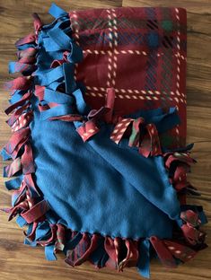 two pieces of blue and red fabric on a wooden floor, one with ruffled edges