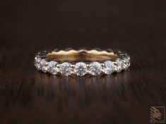 a close up of a wedding ring on a wooden table with dark wood in the background