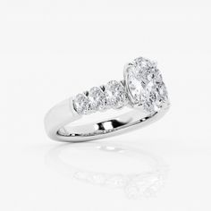 a diamond ring with three stones on the side and an oval shaped center stone in the middle