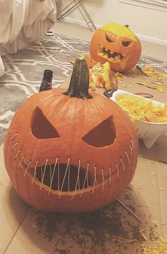 two jack o lantern pumpkins sitting on the floor in front of other halloween decorations