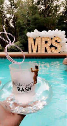 someone is holding up a glass in front of a pool with the word mr and mrs on it