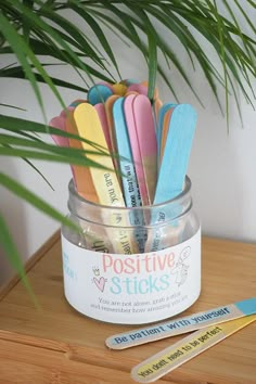 a jar filled with lots of colorful toothbrushes on top of a wooden table