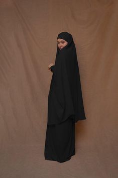 Introducing Black Moira Prayer Umrah Gown with Niqab Feature from Annah Hariri. This beautiful gown is made from high-quality Nada abaya fabric and features super light, stretchy jersey sleeves for ultimate comfort. The elasticated waistband and full skirt ensure a flattering and secure fit, while the khimar can be tied at the back of the head for added coverage.But the best part? This gown can also be transformed into a niqaab with just a few simple stitches. So whether you're performing Umrah, Black Long Khimar For Eid, Traditional Black Dabka Khimar, Black Khimar For Eid, Long Solid Niqab For Eid, Solid Long Niqab For Eid, Long Sleeve Black Khimar For Eid, Black Long Sleeve Khimar For Eid, Modest Black Thobe For Eid, Black Long Sleeve Khimar With Dabka