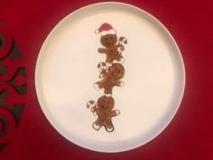 a white plate topped with three gingerbreads on top of a red table cloth