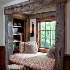 a window seat in the corner of a room with bookshelves and pillows on it