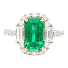 2.22 carat natural Colombian Emerald and Diamond Ring. Centering a lustrous emerald-cut emerald, measuring 10.3 x 6 MM, a desirable elongated shape that gracefully enhances the length of the finger.   The emerald is flanked by two baguette-cut diamonds, totaling 0.50 carats, and adorned by 24 round brilliant-cut diamonds, totaling 0.60 carats, creating a harmonious symphony of step and brilliant cuts. Set in smooth 18k white gold.   Ideal as an engagement ring or cocktail ring.   Ring Details: - Diamond Chandelier Earrings, Diamond Chandelier, Statement Rings Diamond, Platinum Diamond Rings, Colombian Emeralds, Diamond Cocktail Rings, Diamond Drops, Platinum Ring, Diamond Pendant Necklace