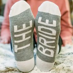 someone's feet wearing socks with the words bride printed on them, sitting on a bed