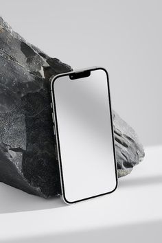 an iphone sitting on top of a rock next to a piece of stone with a blank screen