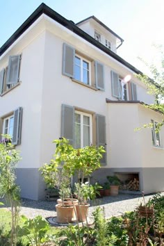 a large white house with lots of windows and plants in the front garden area outside